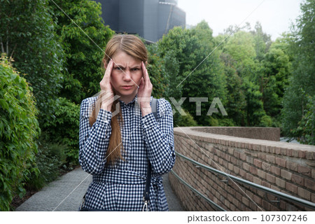 Girl with a headache on the street Girl with a headache on the street 107307246