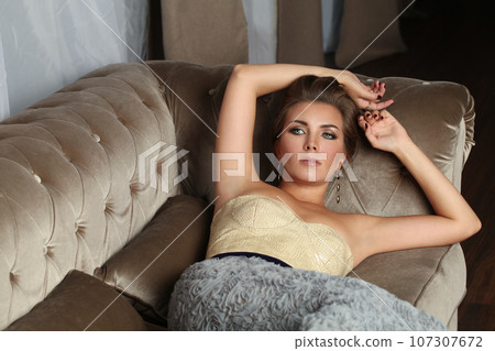 Nice perfect brunette model woman with makeup resting on sofa indoor 107307672