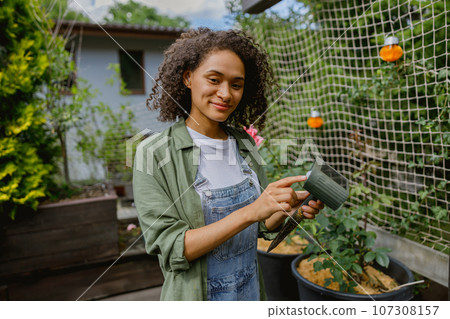 Woman gardener holding a lantern for the garden solar powered standing on garden background Woman gardener holding a lantern for the garden solar powered standing on garden background 107308157