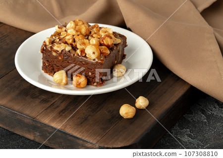 Brownie cake with nuts topping on plate close up 107308810
