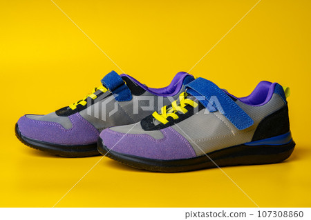 Violet-blue female sneakers on yellow studio background 107308860