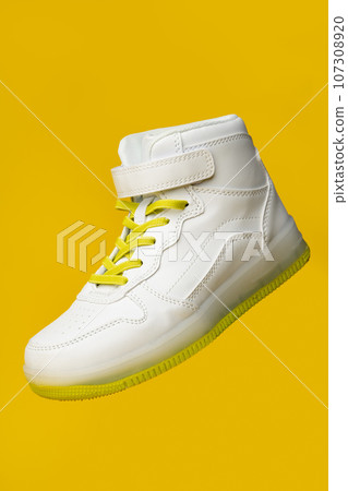 White sneakers with yellow neon laces on yellow background White sneakers with yellow neon laces on yellow background 107308920
