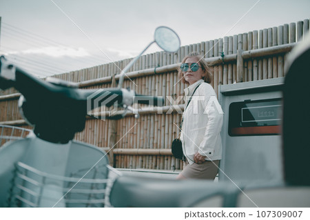 asian woman standing in gas station with female motorcycle forground asian woman standing in gas station with female motorcycle forground 107309007