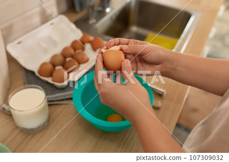 woman breaks egg shells to make breakfast 107309032
