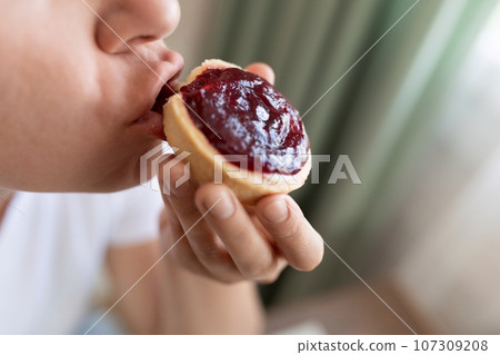 young woman snacking on sweet unhealthy food young woman snacking on sweet unhealthy food 107309208