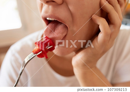 Young woman feels hungry and takes a bite of strawberry 107309213