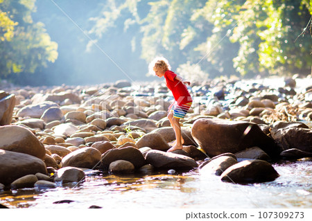 Child hiking in mountains. Kids at river shore. Child hiking in mountains. Kids at river shore. 107309273