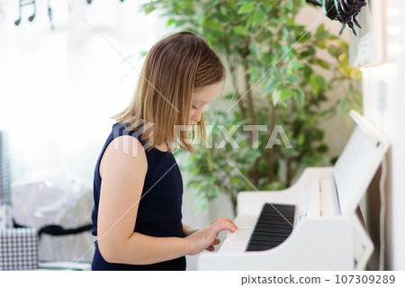 Child playing piano. Kids play music. 107309289