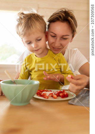 little Caucasian blond son and mother having breakfast with delicious food 107309568