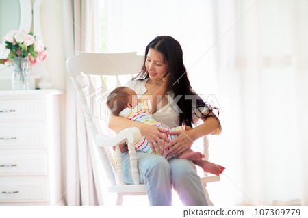 Mother nursing baby at home. Breastfeeding infant. 107309779