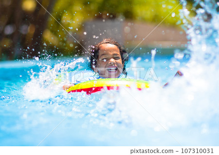 Child in swimming pool on toy ring. Kids swim. 107310031