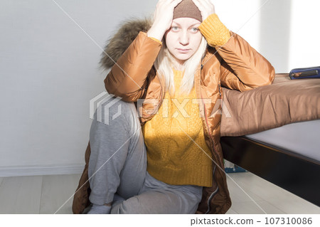 A girl in a yellow sweater and jacket holds her head with her hands from big problems and stress. 107310086