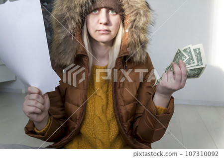 A man in a yellow sweater and jacket with documents in his hands and money.  107310092