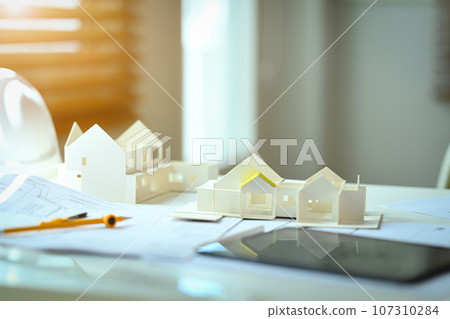 House model, compass and blueprints on architectural workstation. Building, construction and architect concept House model, compass and blueprints on architectural workstation. Building, construction and architect concept 107310284