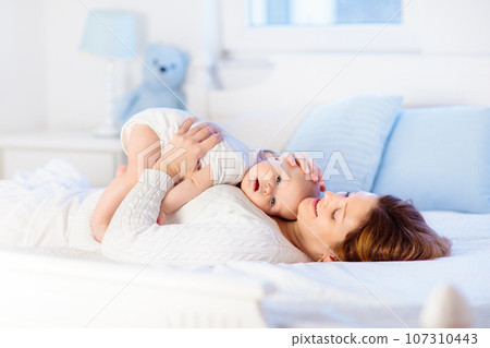 Mother and baby on a white bed Mother and baby on a white bed 107310443