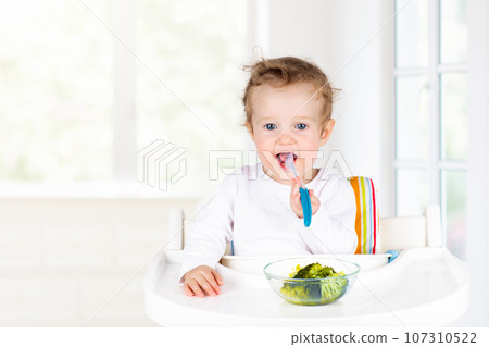 Baby eating vegetables. Solid food for infant. 107310522