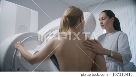 Female doctor adjusts digital mammograph before screening procedure 107313413