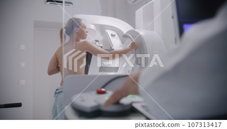 Radiologist pushes button to activate digital mammograph 107313417