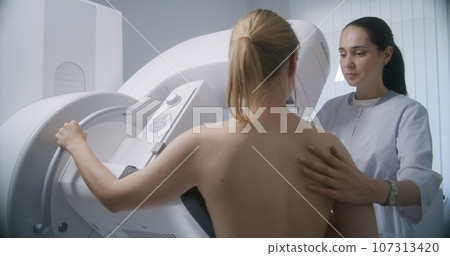 Female doctor adjusts digital mammograph before screening procedure 107313420