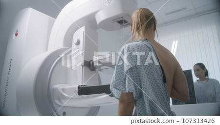 Female doctor adjusts modern mammogram machine for patient 107313426