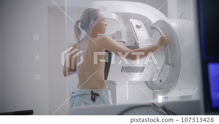 Radiologist pushes button to activate digital mammograph 107313428