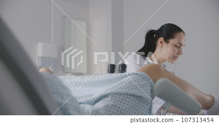 Woman lies on gynecological chair during colposcopy procedure 107313454