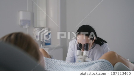 Female gynecologist uses colposcope, takes tests from woman 107313460