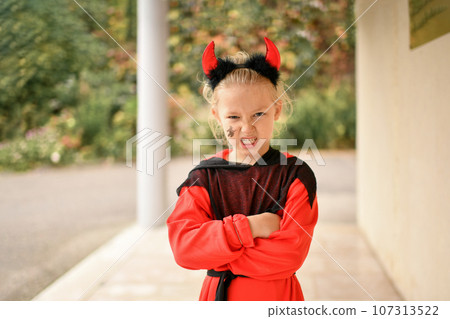 A girl dressed as a devil with horns 107313522