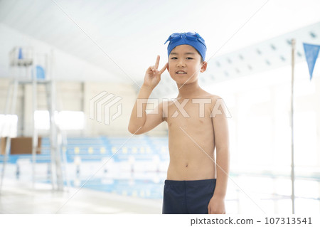 Boy doing peace sign at indoor pool 107313541