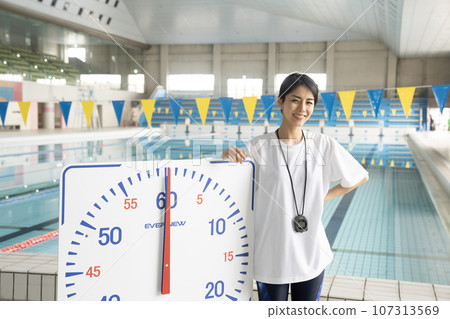 A woman measuring her time in an indoor pool A woman measuring her time in an indoor pool 107313569