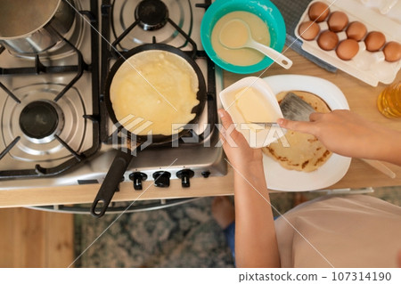 a woman makes pancakes on a griddle 107314190