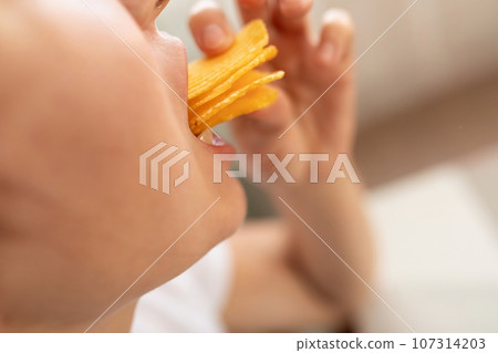 a young woman overeats on chips while on a diet. eating disorder a young woman overeats on chips while on a diet. eating disorder 107314203