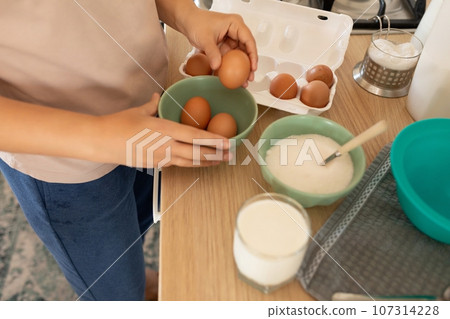 hand pulls out an egg to make scrambled eggs 107314228