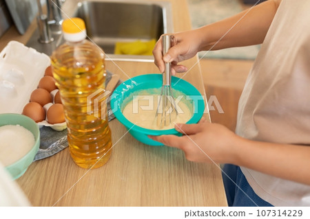a woman makes dough using sunflower oil a woman makes dough using sunflower oil 107314229