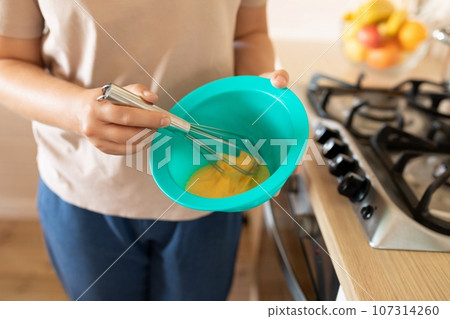 beating eggs in a deep bowl to make breakfast beating eggs in a deep bowl to make breakfast 107314260