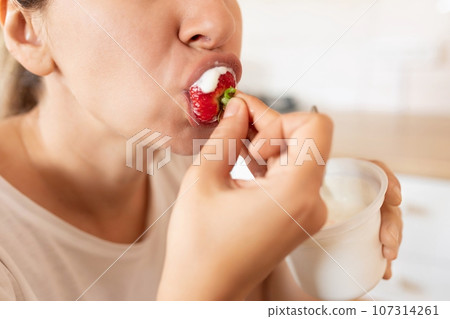 woman eats right and eats strawberries during snack 107314261