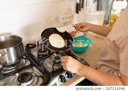 the process of making pancakes on a griddle in the home kitchen the process of making pancakes on a griddle in the home kitchen 107314346