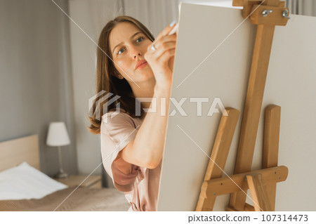 Pretty talented woman painter painting close-up on easel making colorful sketches creating wonderful art. Beautiful female artist painting with pastel. Creativity and imagination concept Pretty talented woman painter painting close-up on easel making colorful sketches creating wonderful art. Beautiful female artist painting with pastel. Creativity and imagination concept 107314473
