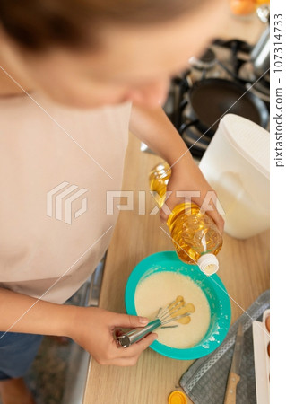a woman makes dough using sunflower oil a woman makes dough using sunflower oil 107314733