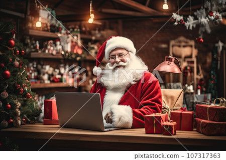 Santa Claus sits in the warehouse of his factory in front of laptop monitor. Santa Claus sits in the warehouse of his factory in front of laptop monitor. 107317363