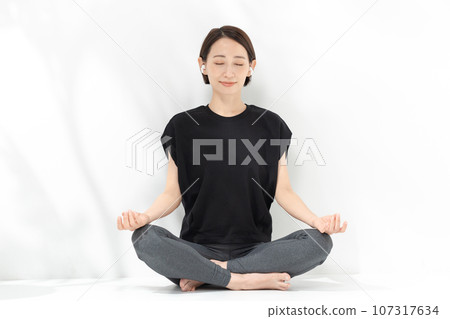 Woman doing yoga zazen cross-legged 107317634