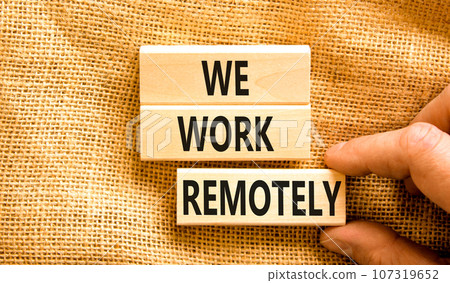 We work remotely symbol. Concept words We work remotely on wooden block. Beautiful canvas table canvas background. Businessman hand. Business we work remotely concept. Copy space. 107319652