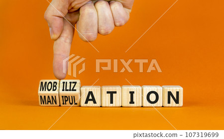 Mobilization or manipulation symbol. Concept words Mobilization Manipulation on wooden cubes. Beautiful orange background. Psychologist hand. Psychology mobilization manipulation concept. Copy space. 107319699