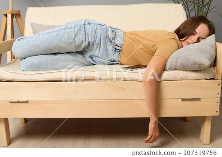 Exhausted Caucasian woman lying on sofa in living room sleeping after hard-working day tired female falling asleep on couch at home, take nap or daydream. Exhausted Caucasian woman lying on sofa in living room sleeping after hard-working day tired female falling asleep on couch at home, take nap or daydream. 107319756