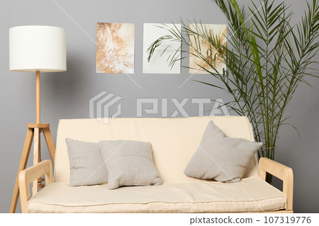 Modern living room interior with design sofa, green flower, picture on the wall, lamp, pillows on couch. 107319776