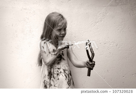 A girl in a dirty dress shoots from a slingshot 107320028