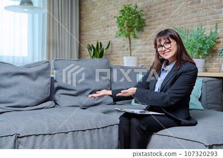 Portrait of female psychologist with clipboard sitting on couch in office 107320293