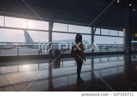 Young woman at the airport window looking to the planes Young woman at the airport window looking to the planes 107320711