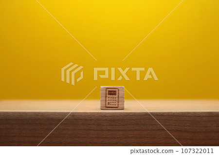 木立方體黃色背景的前視圖，桌上有一個小計算器標記 107322011