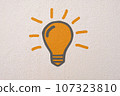 Abstract orange thinking light bulb on concrete wall background 107323810